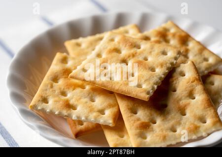 Viele Cracker auf einer Platte, die auf einem weißen Hintergrund mit Platz platziert ist. Nahaufnahme. Stockfoto