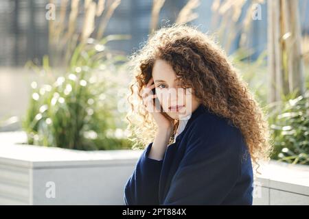 Porträt einer niedlichen jungen Frau mit braunen lockigen Haaren Stockfoto