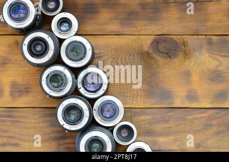 Mehrere Fotolinsen liegen auf braunem Holzhintergrund. Platz für Text Stockfoto