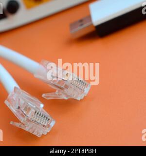 Internet-Router, tragbarer USB-wi-Fi-Adapter und Internetkabelstecker liegen auf hellem orangefarbenen Hintergrund. Für die Internetverbindung erforderliche Elemente Stockfoto