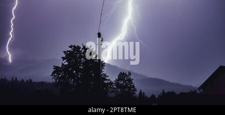Zwei Blitzschläge in der Nacht auf die Berge. Nächtliche Berglandschaft. Blitze von Licht von Donner und Blitz. Bild herunterladen Stockfoto