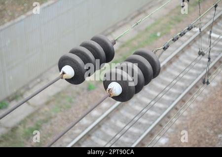 Elektrische Isolatoren auf die fahrdrähte auf dem Hintergrund einer unscharfen Bahntrasse. Makro Foto mit selektiven Fokus Stockfoto