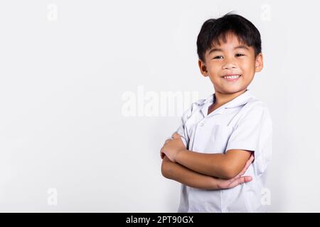 Asiatisch Kleinkind lächeln glücklich tragen Student thai uniform rote Hose stehen mit Armen gefaltet im Studio Schuss isoliert auf weißem Hintergrund, Porträt wenig c Stockfoto