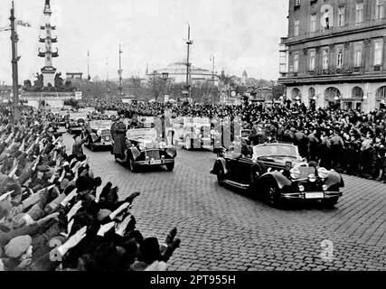 Jubelnde Menschenmassen jubeln die Hitler-Autokolonne an und betreten die Praterstraß im Zentrum von Wien. Im Hintergrund links das Tegetthoff-Denkmal. Stockfoto