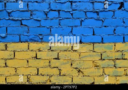 Eine alte Mauer in den Farben der Ukrainische Flagge bemalt. Gelb und Blau auf einem verlassenen und beschädigte Mauer. Das Konzept der Stärke von Stockfoto