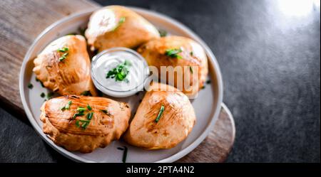 Zusammensetzung mit einem Teller aus im Ofen gebackenen Pierogi Stockfoto