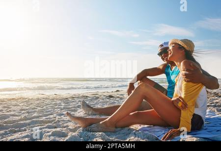 Lassen Sie sich vom Meer überraschen. Ein glückliches Paar, das an einem sonnigen Tag am Strand saß. Stockfoto