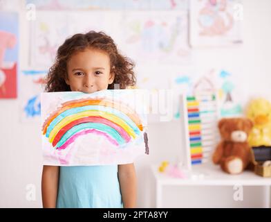 Dont Sie lieben nur die Farben. Ein kleines Mädchen hält ein Bild, das sie von einem Regenbogen gemalt Stockfoto