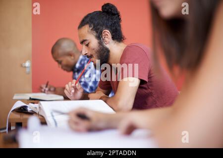 Für eine bessere Zukunft – College Education. Ein junger Schüler in der Klasse, der neben seinen Klassenkameraden studiert Stockfoto