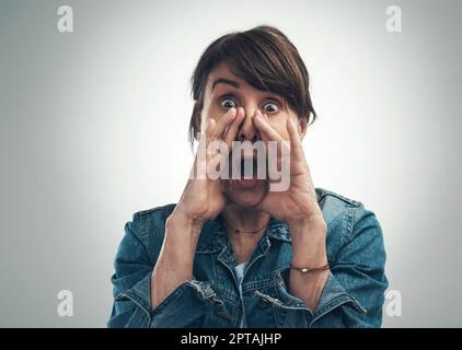 Hey, hört zu. Studioporträt einer Seniorin, die vor grauem Hintergrund schreit Stockfoto