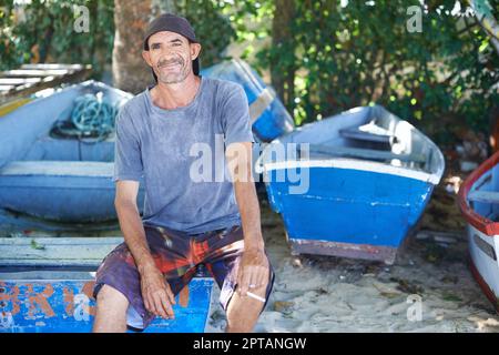 Angeln ist mein Leben. Porträt eines zerklüfteten Fischers, der auf einem Fischerboot sitzt Stockfoto