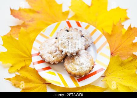 Farbige Cupcakes auf einer Platte und gelben Blätter im Herbst Stockfoto