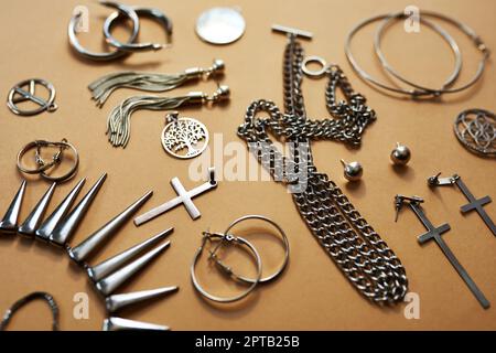 Sag es mit Silber. Studioaufnahme einer Auswahl an Silberschmuck vor braunem Hintergrund Stockfoto