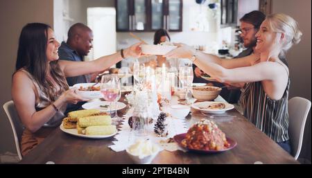 Lasst uns feiern gehen. Eine Gruppe junger Freunde, die zu Hause ein festliches Essen zusammen haben Stockfoto