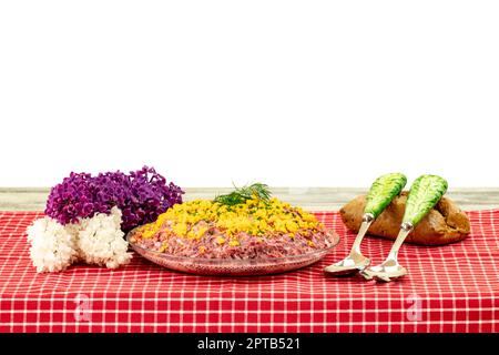 Traditioneller russischer Salat mit dem Namen Hering unter einem Pelzmantel. Traditionelle russische Küche auf einem rustikalen Holztisch isoliert auf weißem Hintergrund. Co Stockfoto