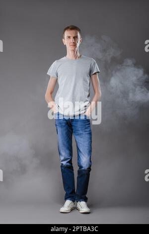 Mittleres Alter Mann in Jeans mit Händen in den Taschen und t-shirt auf grauem Hintergrund Stockfoto