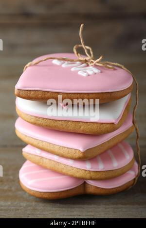 Ein Stapel dekorierter herzförmiger Kekse auf einem Holztisch, Nahaufnahme. Valentinstag-Leckerbissen Stockfoto