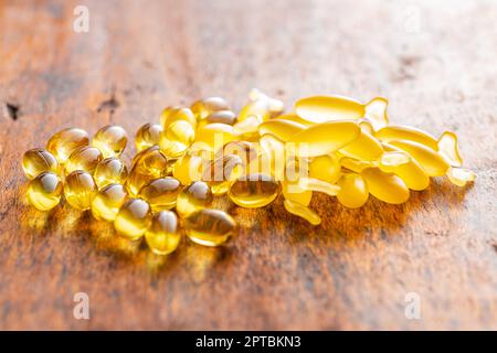 Fischöl-Kapseln. Gelbe Omega 3 Pillen auf dem Holztisch. Stockfoto