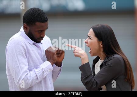 Wütende Frau schimpft auf der Straße vor einem schwarzen Mann Stockfoto