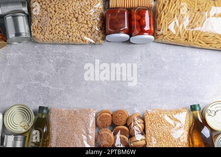 Verschiedene Produkte auf einem hellgrauen Tisch, flach liegend mit Platz für Text. Lebensmittelspende Stockfoto