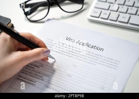 Person Füllt Das Visa-Antragsformular Am Schreibtisch Aus Stockfoto
