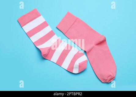 Verschiedene pinkfarbene Socken auf hellblauem Hintergrund, flach liegend Stockfoto