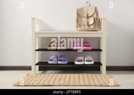 Aufbewahrungsbank mit Paar Gummipantoffeln im Zimmer Stockfoto