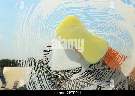 Person, die Glas mit Schwamm reinigt, Sicht von innen Stockfoto