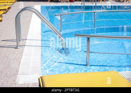 Swimmingpool (im Freien) mit Leiter und Geländern an sonnigen Tagen Stockfoto