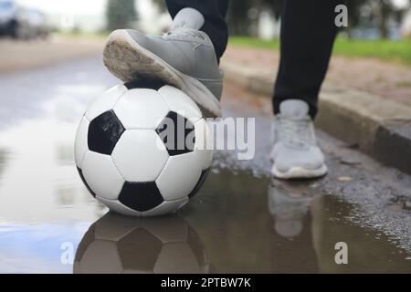 Mann mit Fußball in der Nähe der Pfütze, Nahaufnahme Stockfoto