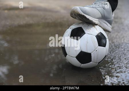 Mann mit Fußball in der Nähe der Pfütze, Nahaufnahme. Platz für Text Stockfoto