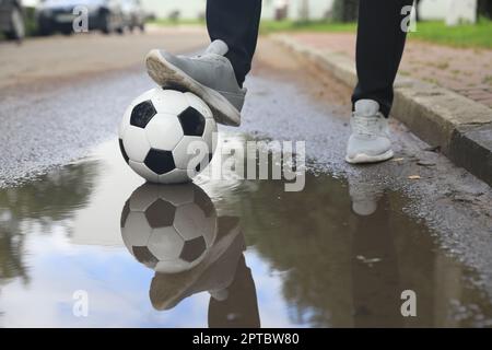 Mann mit Fußball in der Nähe der Pfütze, Nahaufnahme Stockfoto