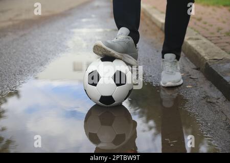 Mann mit Fußball in der Nähe der Pfütze, Nahaufnahme Stockfoto