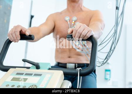 Patient während des Belastungs-EKGs auf einem stationären Fahrrad Stockfoto