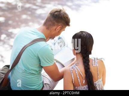 Teamwork macht den Traum wahr. Zwei Schüler, die draußen zusammen ein Buch lesen Stockfoto