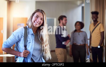 Meine Erfolgsgeschichte beginnt hier mit meinem Studium. Porträt eines Universitätsstudenten, der auf einem Flur auf dem Campus steht Stockfoto