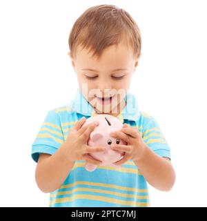 Es fühlt sich so voll an. Studiofoto eines kleinen Jungen, der auf ein weißes Sparschwein schaut Stockfoto