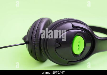 Schwarz Kopfhörer liegt auf einem farbenfrohen Pastelltönen grünen Hintergrund. Musik Konzept Stockfoto