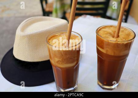 Traditioneller griechischer kalter Kaffee Frappe mit Milchschaum, Instantkaffee und Eiswürfeln in einem großen Glas aus der Nähe des Cafés. Stockfoto