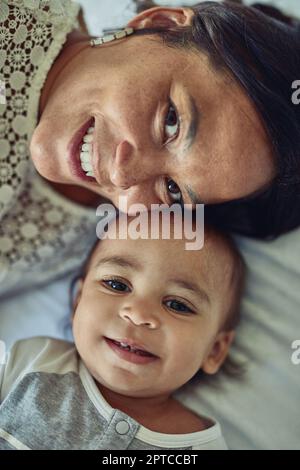 Ich bin sehr glücklich, wenn ich mich mit meinem kleinen Jungen einlasse. Eine Mutter und ihr liebenswerter Sohn liegen zu Hause im Bett Stockfoto