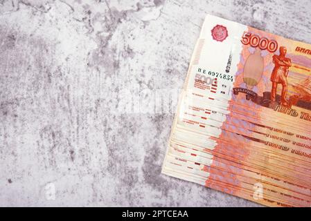 Russische Bargeld-Banknoten im Wert von 5.000 Rubel, das Bündel liegt auf grauem Hintergrund, es gibt Platz für eine Inschrift und Text. Layout, Modell. Stockfoto