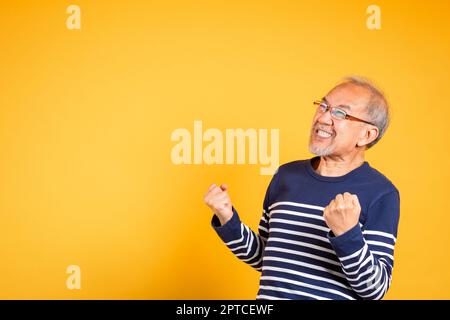 Porträt lächelnd Senior alten Mann Lebensstil er Arme angehoben, um seinen Erfolg zu feiern, glücklich asiatischen älteren Mann mit Brille aufgeregt sagen ja Geste wie w Stockfoto