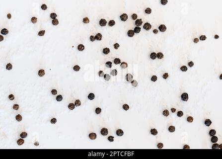 Tafelsalz und schwarze Pfefferkörner auf weißem Hintergrund Stockfoto