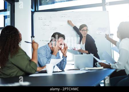 Ihr Punkt ist völlig irrelevant. Eine gestresste Geschäftsfrau, die während eines Meetings mit ihren Kollegen in der Vorstandsetage die Beherrschung verliert Stockfoto