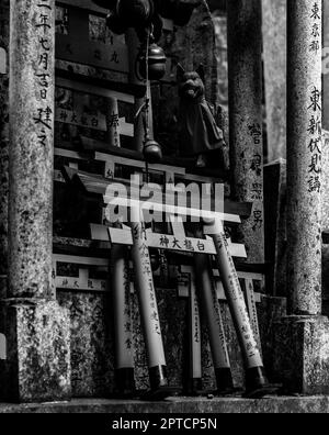 Ein schwarz-weißes Bild von gestapelten Miniatur-Torii-Toren am Fushimi Inari Taisha-Schrein. Stockfoto