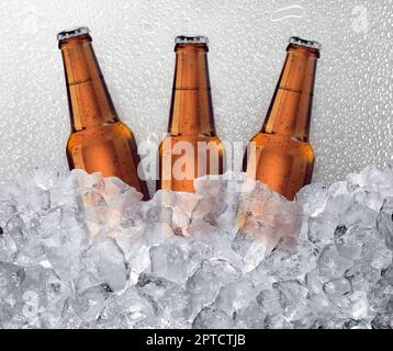 Drei Bierflaschen werden in Eiswürfeln abgekühlt. Hintergrund für Wassertropfen Stockfoto