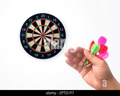 Die menschliche Hand wirft die Zielscheibe des Darts auf das Darts-Brett. Die Hand eines Mannes wirft einen Pfeil auf das Ziel Stockfoto