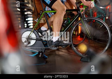 Mann beim Radfahren geschossen. Nahaufnahme beim Treten des männlichen Beins. Fitness-Cardio-Training im Sportclub Stockfoto