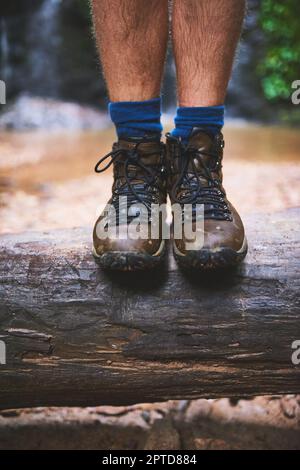 Gehen Sie dorthin, wo Ihre Wanderschuhe Sie hinführen. Ein nicht identifizierbarer Wanderer, der auf einem Baumstamm im Dschungel steht Stockfoto