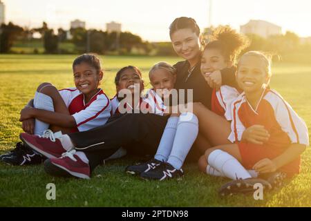 Fußball, Team und Kinder auf dem Sportplatz mit Trainer für Training, Fußballveranstaltung oder Sport lernen. Porträt von Lehrern und Fitnesschülern mit smi Stockfoto